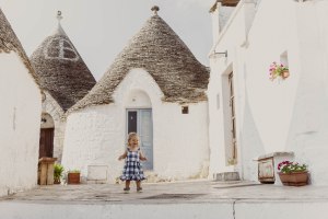 Image of 18-month-old Florence lovingly exploring the Trulli in Alberobello, Italy, a UNESCO World Heritage site known for its unique cone-shaped houses, providing a charming backdrop for her adventurous spirit.